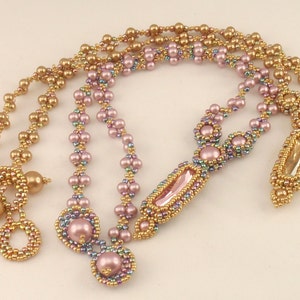 May include: A multi-strand beaded necklace with a pink and gold color scheme. The necklace features a pendant with a clear crystal and a beaded design.