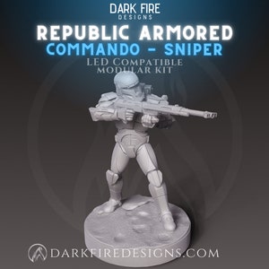 May include: A gray, 3D-printed figurine of a Republic Armored Commando Sniper, holding a rifle. The figure is on a circular base with the text "DARK FIRE DESIGNS" and "REPUBLIC ARMORED COMMANDO - SNIPER" in white and blue.