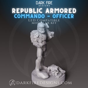 May include: A gray plastic miniature figurine of a Republic Commando officer, standing with a blaster rifle in one hand and a pistol in the other. The figure is part of a modular kit and is compatible with LED lights. The text "Republic Armored Commando - Officer" and "LED Compatible Modular Kit" is visible on the image.