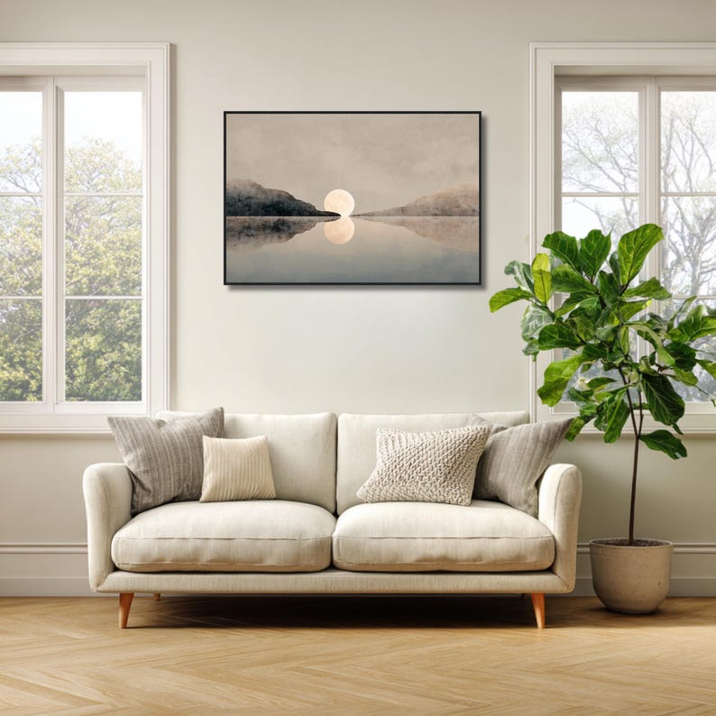 May include: A rectangular wall art print in a black frame featuring a landscape painting of a large, pale moon hovering above a calm body of water between two dark, hazy mountain silhouettes, with a clear reflection visible on the water surface.