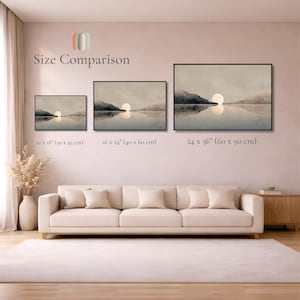 May include: Three framed landscape prints showing a sunset over water with mountains, labeled Size Comparison. Sizes are 12 x 18 inches, 16 x 24 inches, and 24 x 36 inches. The prints are displayed on a wall above a beige sofa in a room.
