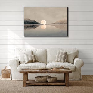 May include: A rectangular wall art print in a black frame featuring a landscape painting of a large, pale moon centered between two dark, silhouetted mountain ranges, with the moon and mountains reflected in the calm, still water below.