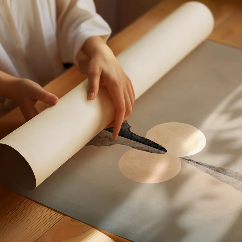 May include: A large, off-white paper scroll being unrolled to reveal a printed graphic. The design features two overlapping pale circular shapes set against a muted, gradient background with a dark, abstract, pointed brushstroke element.