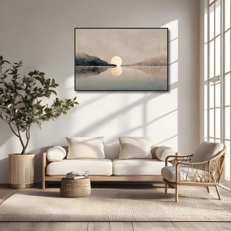 May include: A rectangular wall art print featuring a landscape with a large, pale moon centered above a calm body of water. Dark, silhouetted mountains flank the horizon, with the moon's reflection visible on the water's surface in a muted palette.