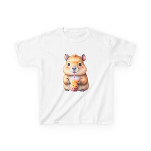 May include: White t-shirt featuring a cute cartoon hamster drinking a boba tea. The hamster is light brown with a pink tongue and is holding a clear cup with a pink straw. The boba tea has brown tapioca pearls.