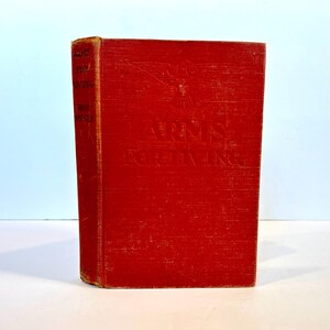 May include: A red hardback book with the title "Arms for Living" embossed on the front cover. The book has a gold eagle design on the front cover.