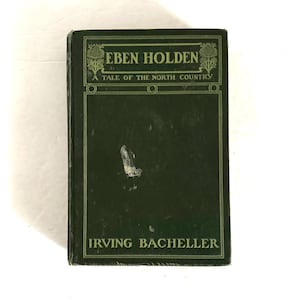 Puede incluir: Un libro antiguo de tapa dura titulado "Eben Holden" de Irving Bacheller. El libro tiene una cubierta verde oscuro con letras doradas y elementos decorativos. El título y el nombre del autor se muestran de forma destacada.