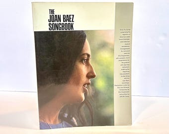 May include: The Joan Baez Songbook, a vintage music book featuring a color photo of Joan Baez on the cover. The book includes sixty-seven songs, arrangements for voice and piano, and complete chord progressions.