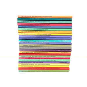 Könnte beinhalten: Ein Stapel bunter Kinderbücher mit Titeln wie "Cactus Coyote" und "The Extraordinary Bubble". Die Buchrücken zeigen eine Vielzahl von Farben, darunter Orange, Grün, Blau und Rosa, mit weißem Text. Die Bücher sind auf weißem Hintergrund gestapelt.