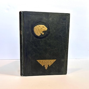 May include: A dark green hardcover book with gold lettering and a gold embossed image of an animal's head on the front cover. The book's title is "Tahoma 1929".