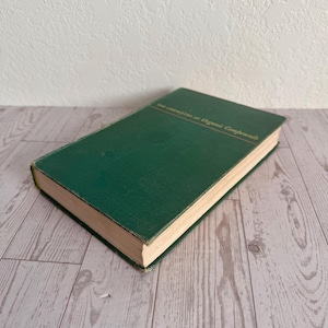 May include: A green hardcover book titled The Chemistry of Organic Compounds with gold lettering on the front cover. The book has light-colored pages visible along the edges and is positioned at an angle to show the front and side profile.