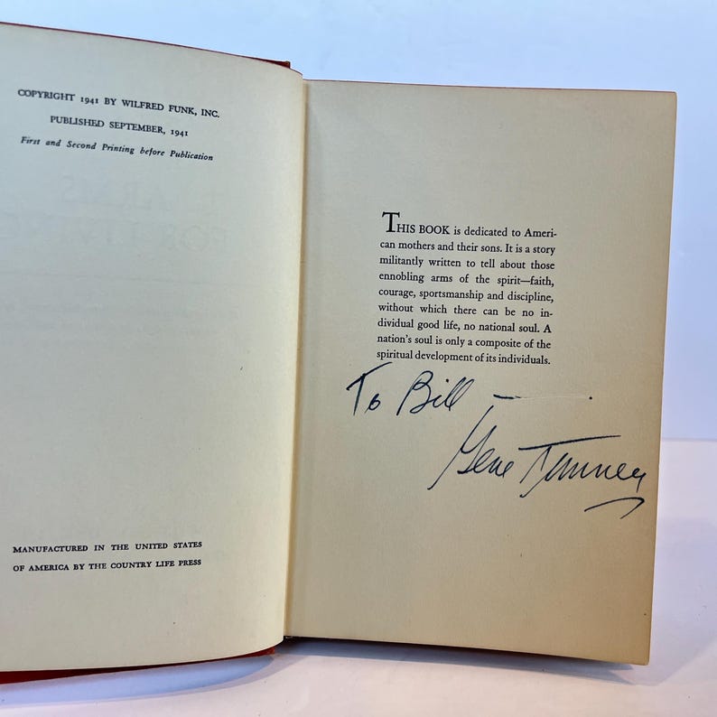 May include: A book with a dedication to American mothers and their sons. The book is titled "This Book is dedicated to American mothers and their sons." The text is written in black ink on a white background. The book is signed "To Bill" with a signature below.
