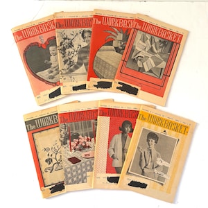 以下が含まれることがあります： ヴィンテージ雑誌「The Workbasket」のコレクション。表紙には、赤ちゃん、フラワーアレンジメント、女性など、さまざまなイラストや写真が掲載されています。雑誌は赤、黄、黒の色合いで、タイトルが大きく表示されています。