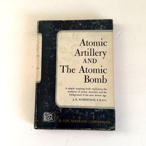 May include: A vintage book titled "Atomic Artillery and The Atomic Bomb" with a black and white cover. The book's title is in large, bold letters, and the cover also includes the author's name and a brief description of the book's contents.