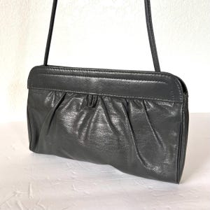 May include: A black leather shoulder bag with a gathered front and a flap closure.