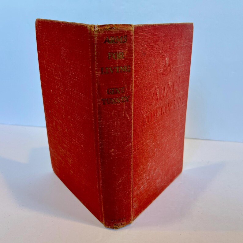 May include: A red hardback book titled "Arms for Living" by Eric F. Goldman. The book has a gold eagle design on the front cover.