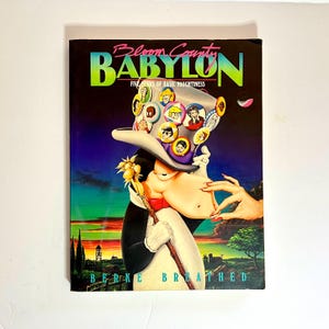 Könnte beinhalten: Ein Buchcover mit einer Comicfigur mit einem großen Hut. Der Hut ist mit bunten Knöpfen mit Gesichtern darauf bedeckt. Der Buchtitel lautet "Bloom County Babylon: Five Years of Basic Naughtiness" von Berke Breathed.