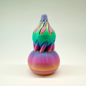 May include: A 3D-printed sculpture with a spherical base and a layered top. The base has a gradient from pink to yellow, and the top features green, pink, and blue. The sculpture has a smooth, textured appearance.