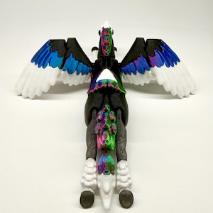 May include: A 3D-printed Pegasus figurine with a black body, white wings with blue and purple accents, and a rainbow-colored mane and tail. The figurine is posed with its wings spread, showcasing the detailed design and vibrant colors.