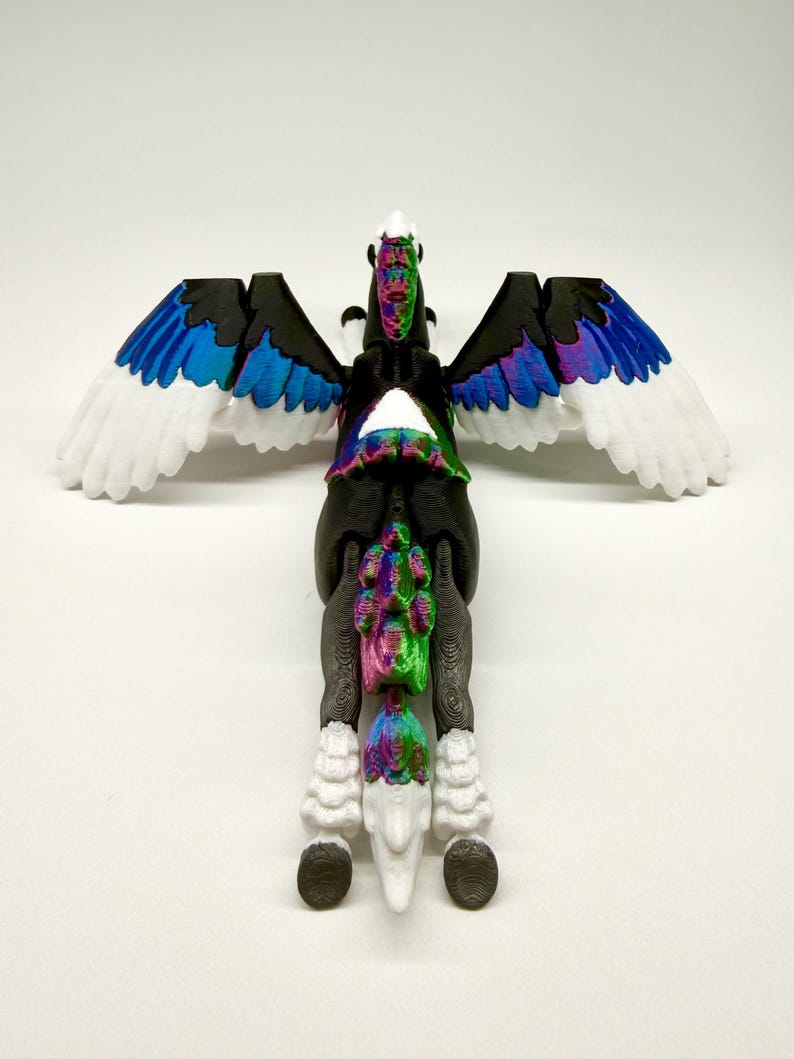 May include: A 3D-printed Pegasus figurine with a black body, white wings with blue and purple accents, and a rainbow-colored mane and tail. The figurine is posed with its wings spread, showcasing the detailed design and vibrant colors.
