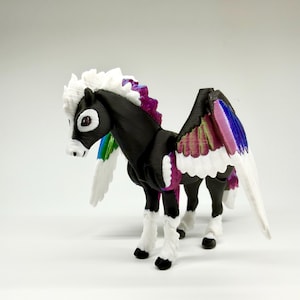May include: A 3D-printed Pegasus figurine with a black body, white mane, and multi-colored wings. The wings feature a gradient of colors including pink, purple, blue, and green. The figurine has white legs with black hooves and a white tail.