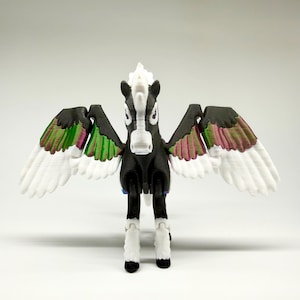 May include: A 3D-printed Pegasus figurine. The black horse has white wings with green and pink accents. The mane and lower legs are white. The figurine is standing with its wings spread.