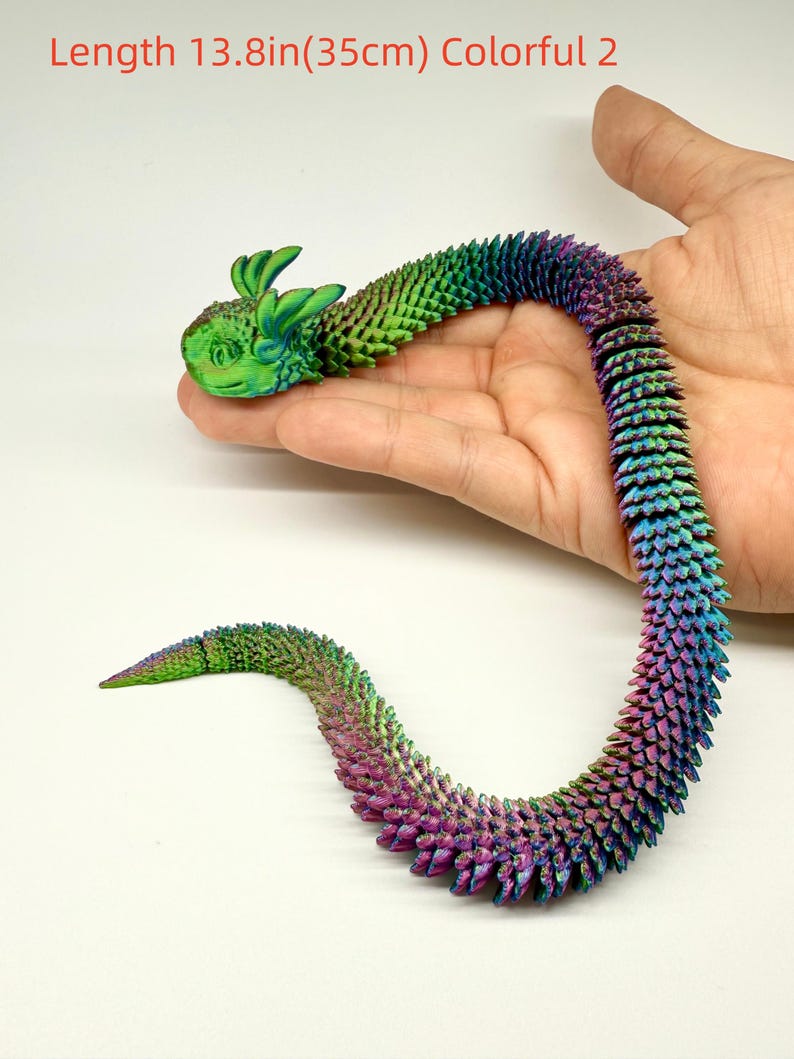 May include: A colorful, articulated dragon toy, approximately 13.8 inches (35cm) long. The dragon features a green head with large ears and a body that transitions from green to purple. The text "Length 13.8in(35cm) Colorful 2" is visible.