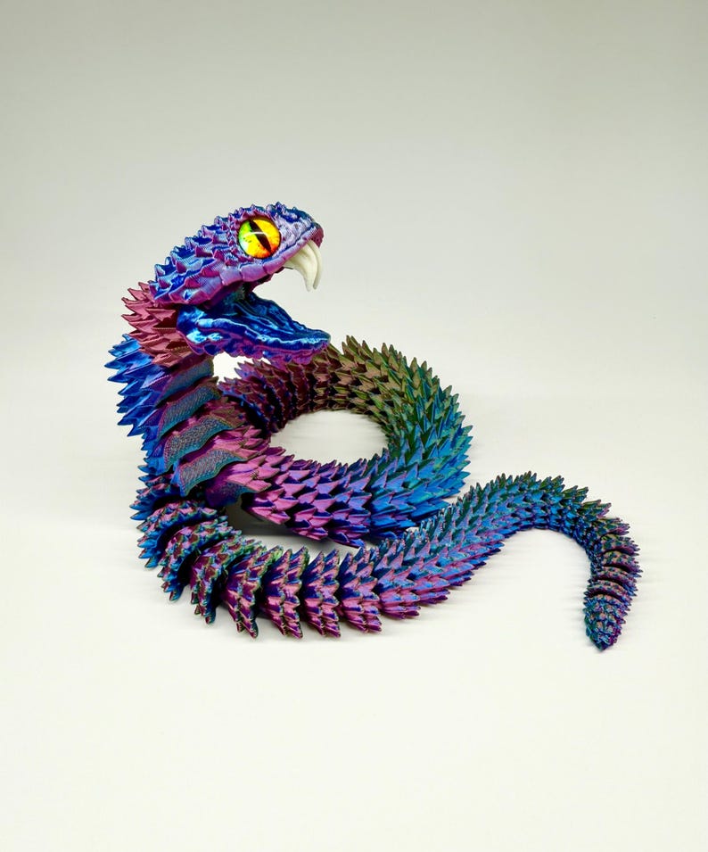 May include: A colorful, articulated snake sculpture with a vibrant gradient of blues, purples, and greens. The snake has a detailed, textured surface, sharp teeth, and a yellow and black eye. The sculpture is a unique decorative item.