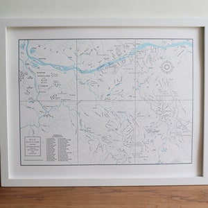 Puede incluir: Un mapa enmarcado del &aacute;rea de Wild Portland, que muestra r&iacute;os, lagos y senderos. El mapa est&aacute; impreso en azul y negro sobre un fondo blanco. El t&iacute;tulo "Wild Portland" est&aacute; impreso en negro en la parte inferior del mapa. El mapa incluye una clave con una lista de cascadas y rutas de senderismo.