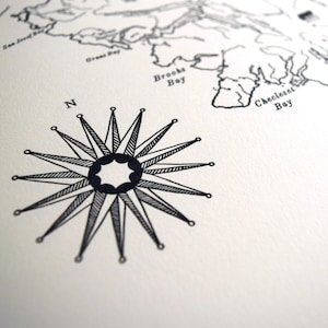 May include: Monochrome nautical map print with a detailed compass rose and a section of coastline. The compass rose is central, with the letter "N" indicating north. The map includes bay names.