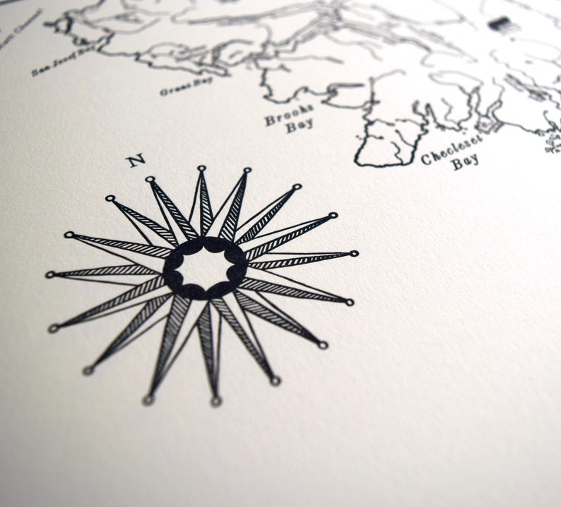 May include: Monochrome nautical map print with a detailed compass rose and a section of coastline. The compass rose is central, with the letter "N" indicating north. The map includes bay names.
