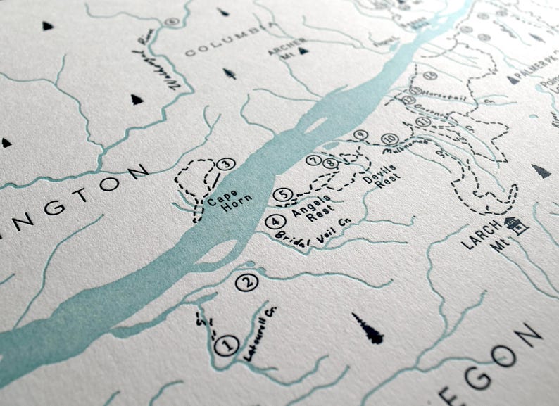 May include: Detailed map print featuring the Columbia River, with Washington and Oregon labeled. The map includes hiking trails, landmarks, and the names Cape Horn, Angels Rest, and Devils Rest. The color palette is primarily white and light blue.