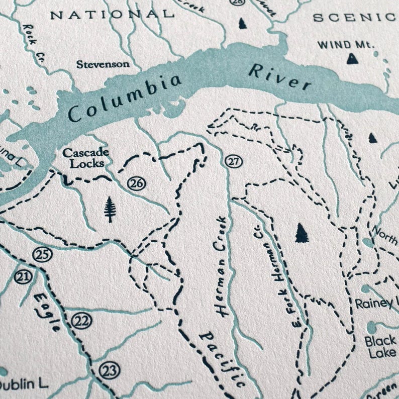 May include: A detailed map print featuring the Columbia River and surrounding areas. The map uses a muted color palette with teal blue for the river and text, and black for the dashed lines and place names. The map includes the text "Columbia River" and "Cascade Locks".