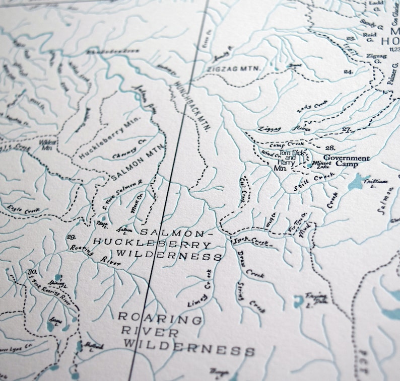 Puede incluir: Un mapa en blanco y negro de un &aacute;rea silvestre con los nombres "Salmon-Huckleberry Wilderness" y "Roaring River Wilderness" impresos en &eacute;l. El mapa muestra r&iacute;os, arroyos, monta&ntilde;as y otras caracter&iacute;sticas geogr&aacute;ficas.