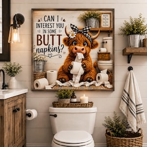 May include: A square wall art print featuring a fluffy brown Highland cow wearing a black and white checkered bow with a daisy. The text reads, Can I interest you in some butt napkins? The cow is surrounded by rolls of white toilet paper.