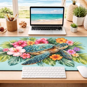 Puede incluir: Alfombrilla de escritorio rectangular con un diseño de acuarela de una tortuga marina rodeada de flores y follaje tropicales. La alfombrilla es de color azul claro con un borde negro. Un teclado y un ratón blancos están en primer plano.