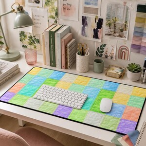 May include: A colorful desk setup featuring a patchwork-style mousepad with a white keyboard and mouse. The desk is adorned with books, stationery, and a small succulent, creating a vibrant and organized workspace.