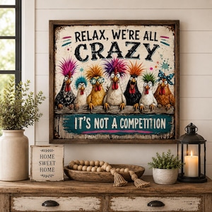 May include: A square wall sign in a dark wood frame featuring seven colourful chickens with wild hairstyles. The text reads, "RELAX, WE'RE ALL CRAZY" at the top and "IT'S NOT A COMPETITION" on a teal background at the bottom, with a distressed, vintage-style finish.