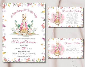 May include: A set of baby shower stationery featuring a watercolor illustration of a bunny in a pink jacket. The invitation includes event details and is surrounded by floral accents. Additional cards request books and a diaper raffle.