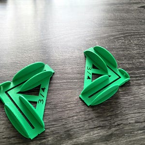 May include: Two green plastic corner brackets with the text "3/4" printed on them. The brackets are designed to help create a 90-degree angle when joining two pieces of wood.