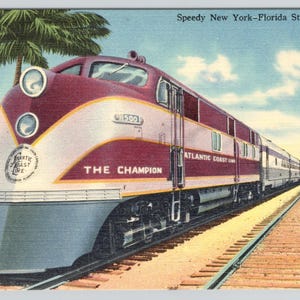 May include: Vintage postcard featuring the "Speedy New York-Florida Streamliner" train, "The Champion." The train is painted in maroon and white with the "Atlantic Coast Line" logo. The scene includes palm trees and a blue sky.