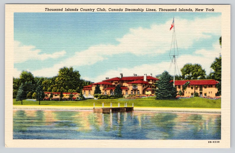 K&ouml;nnte beinhalten: Eine Vintage-Postkarte des Thousand Islands Country Club, Canada Steamship Lines, Thousand Islands, New York. Das Bild zeigt ein gro&szlig;es beiges Geb&auml;ude mit rotem Dach, eine gr&uuml;ne Wiese, einen Holzsteg und einen Fahnenmast am Wasser.