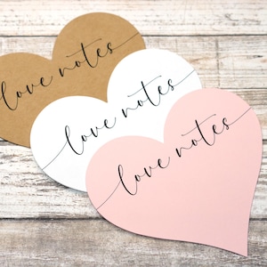 May include: Three heart-shaped cards with the text "love notes" written in black cursive on each card. The cards are brown, white, and pink.