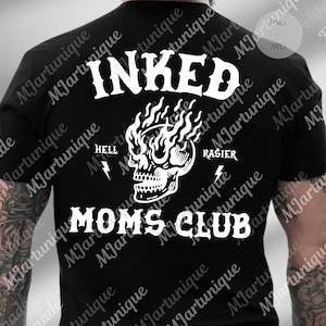 May include: Black t-shirt with a white graphic design. The design features the word "INKED" above a flaming skull, with the words "HELL" and "RASIER" on either side. Below the skull is the text "MOMS CLUB".