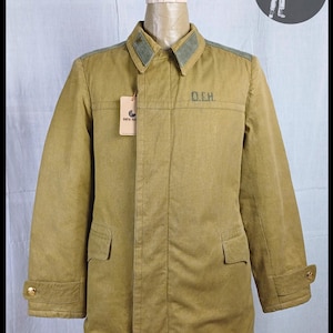 Pode incluir: Uma jaqueta militar marrom com gola verde e um patch que diz "O.C.H."