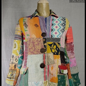 Puede incluir: Chaqueta patchwork con una variedad de patrones de tela coloridos. La chaqueta tiene cuello, tres botones marrones grandes y dos bolsillos delanteros. La chaqueta se exhibe en un maniquí. La etiqueta de la chaqueta dice "TIME RIDER".
