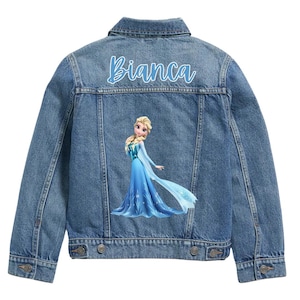May include: A denim jacket with a light blue wash. The back of the jacket features the name "Bianca" in a light blue script above a graphic of a princess in a blue dress.