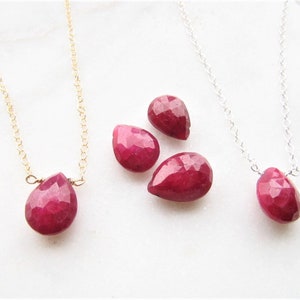 May include: Three necklaces with teardrop-shaped ruby pendants. Two necklaces have silver chains and one has a gold chain.