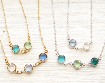 May include: Two delicate necklaces with a gold and silver chain. The gold necklace has three round blue and green gemstones, while the silver necklace has four round green and blue gemstones.