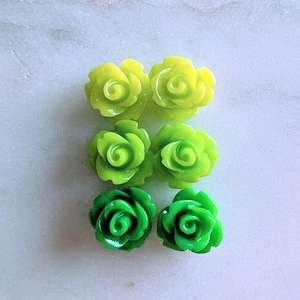 May include: Six green and yellow resin rose flower embellishments. The roses are in two shades of green, with the top two roses being a lighter shade of green and the bottom two roses being a darker shade of green.